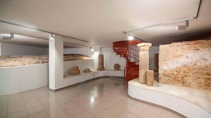 Sala de exposiciones con elementos arqueológicos y escalera roja