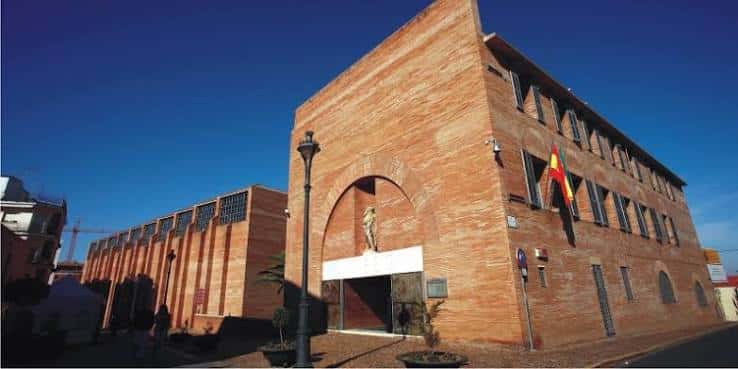 Vista exterior del Museo Nacional de Arte Romano en Mérida con fachada de ladrillo y bandera española