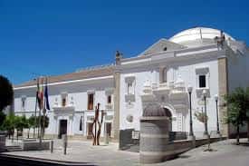 Vista exterior de la Asamblea de Extremadura en Mérida con fachada blanca y cúpula bajo cielo azul