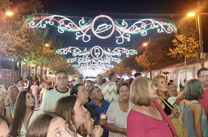 Vista nocturna de la feria con decoraciones de luces y público en la calle