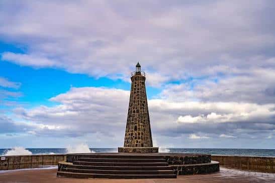 Vista frontal del Faro de Bajamar con cielo parcialmente nublado y mar al fondo