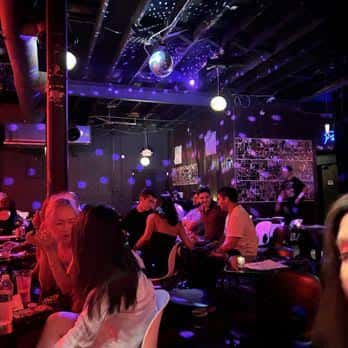Interior del club con ambiente nocturno, luces azules y gente socializando