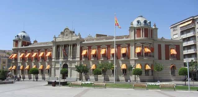 Fachada principal del palacio con banderas y toldos naranjas bajo un cielo despejado