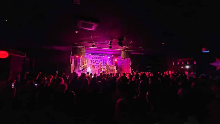 Concierto en vivo con banda en el escenario bajo luces de neón