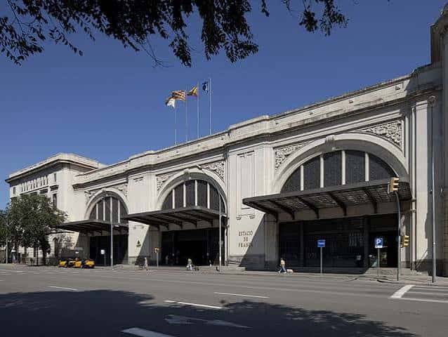 Fachada exterior de la Estació de França con banderas y arquitectura clásica