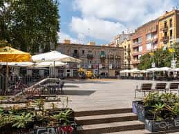 Área central de la plaza con mobiliario urbano, plantas y sombrillas de terrazas