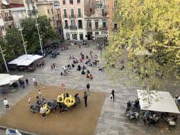 Vista aérea de la Plaça del Sol con personas disfrutando del espacio y áreas de juego infantiles