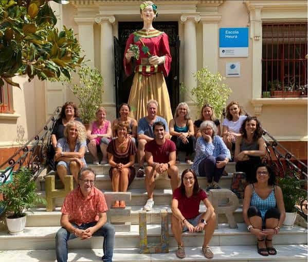 Grupo de personas posando en las escaleras de la entrada de la Escola Heura con estatua decorativa