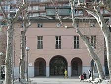 Vista frontal del edificio rodeado de árboles, mostrando su arquitectura clásica y entrada principal
