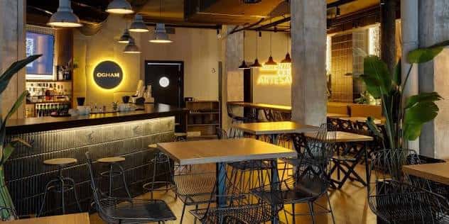 Interior de la cervecería Ogham con barra iluminada y mesas