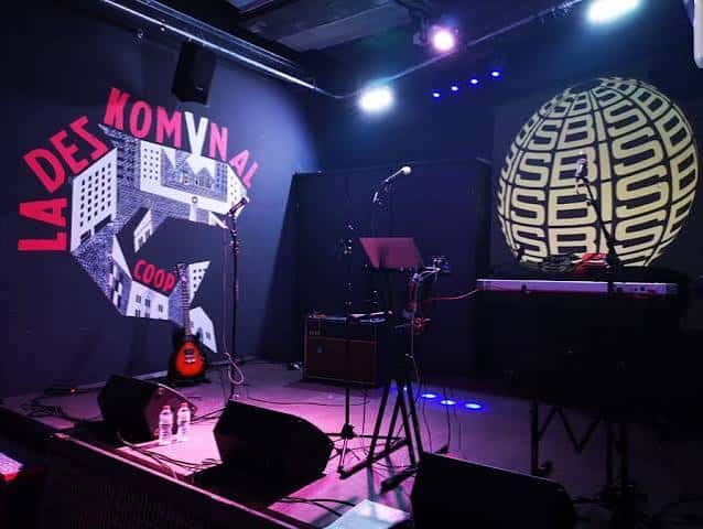 Escenario del local con equipo de sonido y proyección del logo