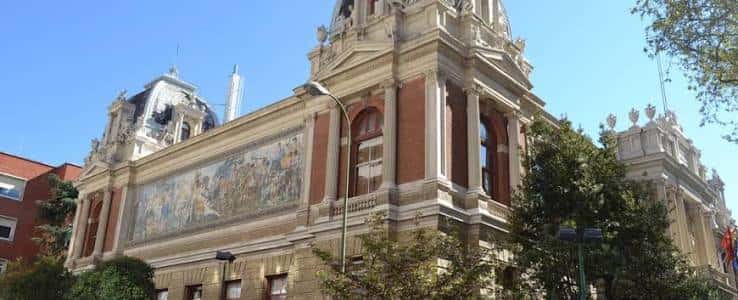 Vista lateral del edificio con murales decorativos y cúpulas bajo cielo azul
