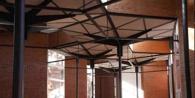 Detalle del techo estructural con vigas metálicas y paneles hexagonales en el interior del pabellón