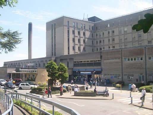 Vista exterior del Derriford Hospital en Plymouth durante el día con personas y vehículos en la entrada