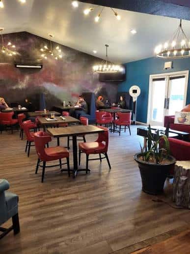 Interior del local con mesas, sillas rojas y decoración moderna con murales