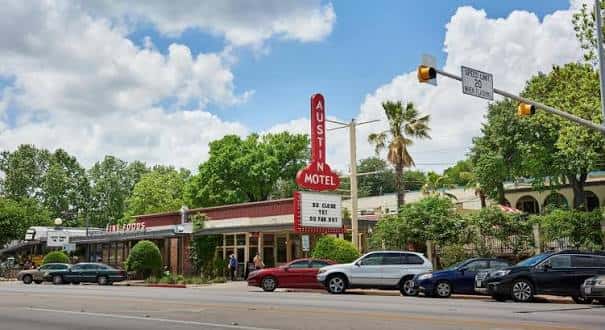 Vista diurna del Austin Motel con su icónico letrero vertical rojo y estacionamiento frente a la calle