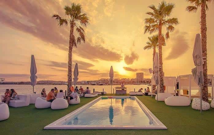Vista panorámica del Marmarela Beach Club al atardecer con piscina y zona de lounge