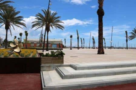 Plaza abierta con escaleras, palmeras y escultura metálica, ideal para eventos al aire libre