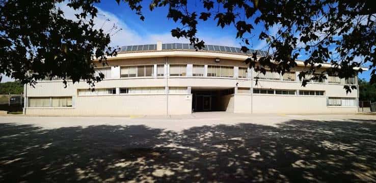Fachada principal de la escuela con árboles al frente