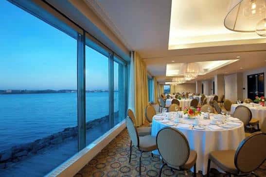 Sala de eventos interior con mesas decoradas y vista al mar