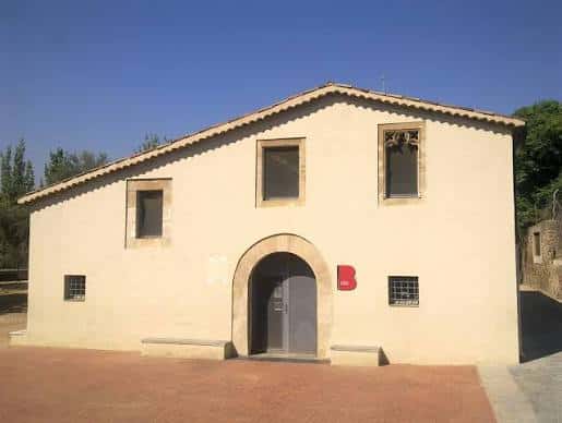 Fachada principal de la masía Ca l'Arnó con puerta de arco y ventanales de piedra