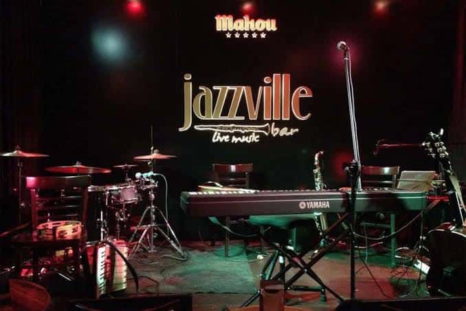 Escenario del Jazzville con instrumentos musicales y logotipo del bar