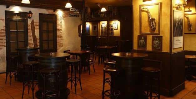 Área de bar del Jazzville con mesas altas y decoración temática de jazz