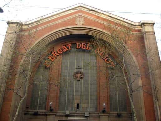 Entrada principal histórica del mercado con arco de ladrillo y letrero 'Mercat del Ninot'