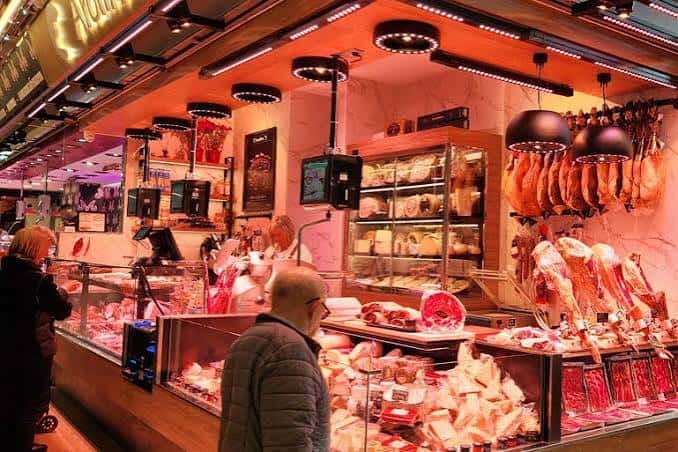 Interior del mercado mostrando puestos de carnicería y embutidos con iluminación cálida