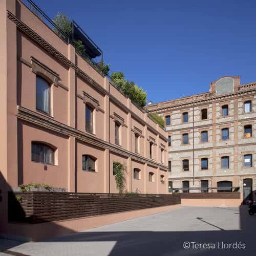 Fachada lateral del edificio con ventanas arqueadas y detalles arquitectónicos en tonos terracota