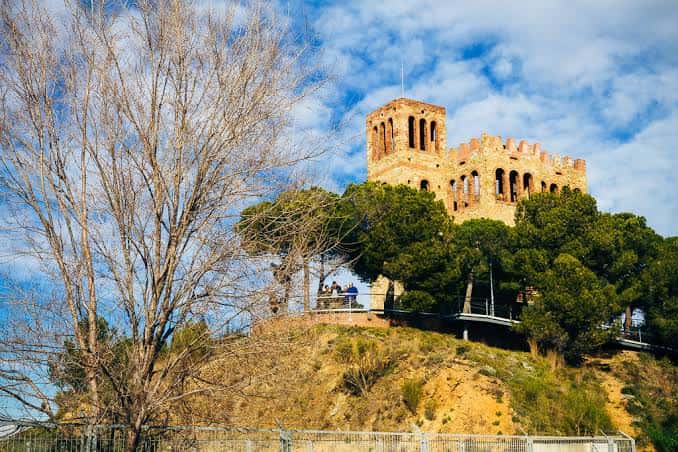 Castillo de Torre Baró en primer plano con cielo azul y árboles alrededor