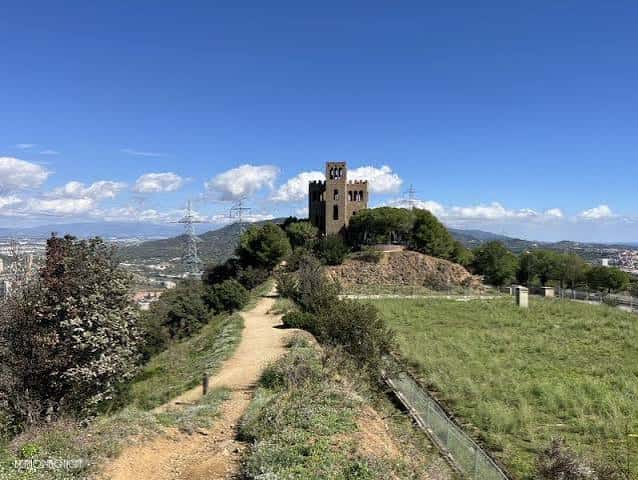 Vista panorámica del castillo desde un sendero con paisaje urbano al fondo