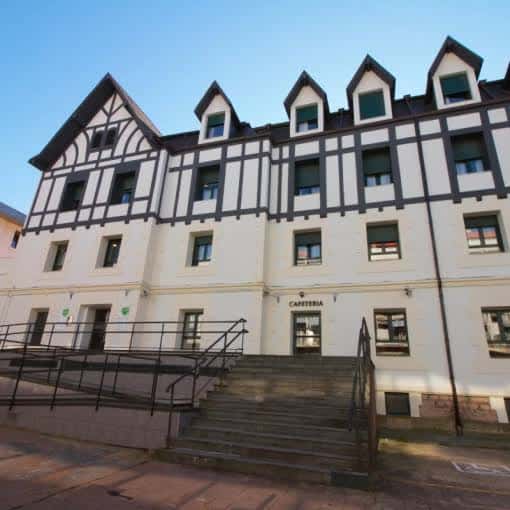 Entrada principal de la residencia con rampa de acceso y señalización de cafetería