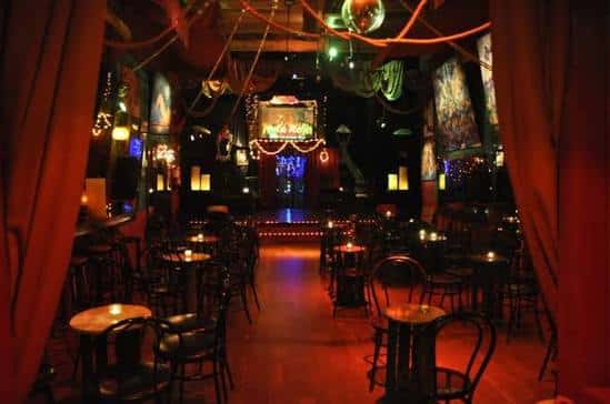 Ambiente nocturno del local con mesas y decoración teatral
