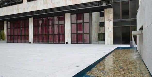 Patio interior con fuente y grandes ventanales con cortinas rojas