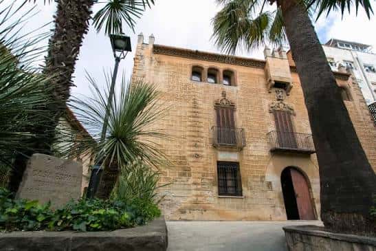 Fachada histórica de Can Riera con palmeras y detalles arquitectónicos