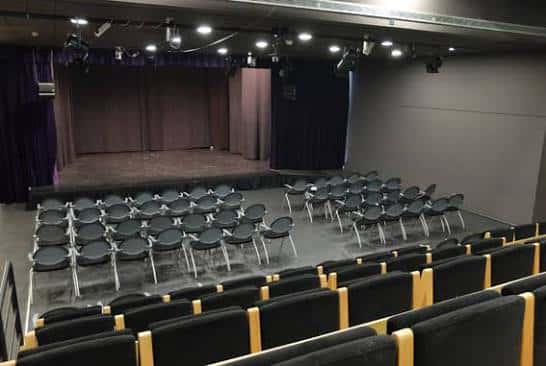 Interior del auditorio con escenario y butacas dispuestas para evento