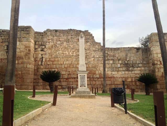 Obelisco central en la plaza rodeado de palmeras y jardines frente a las ruinas históricas