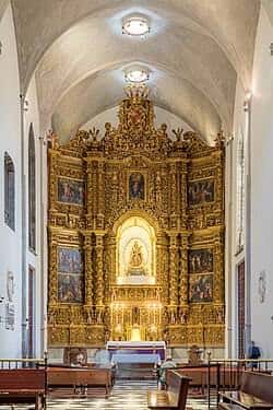 Altar principal dorado con detalles barrocos y escultura central iluminada