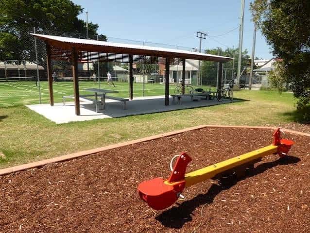 Área de picnic cubierta con mesas y un columpio en primer plano