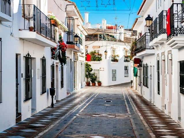 Calle empedrada del casco antiguo con fachadas blancas y balcones decorados