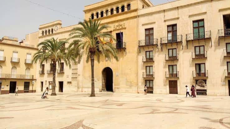 Vista frontal del Ayuntamiento de Elche con palmeras y plaza