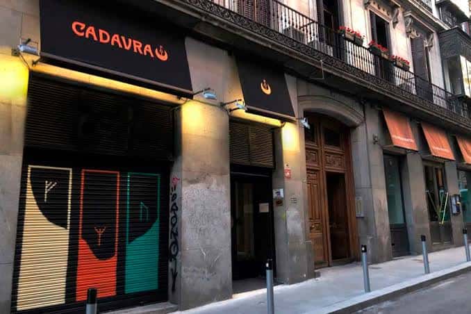 Fachada exterior de Cadavra Club con letrero iluminado y puertas cerradas