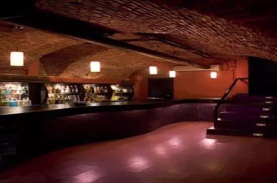 Bar interior con techo de bóveda de ladrillo y barra bien surtida