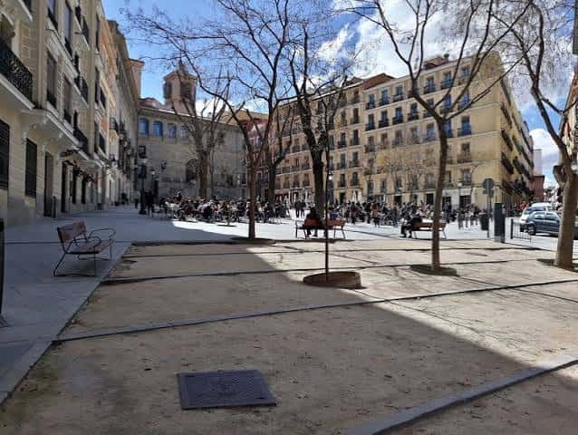 Plaza de la Paja con personas sentadas en bancos y arquitectura tradicional madrileña al fondo