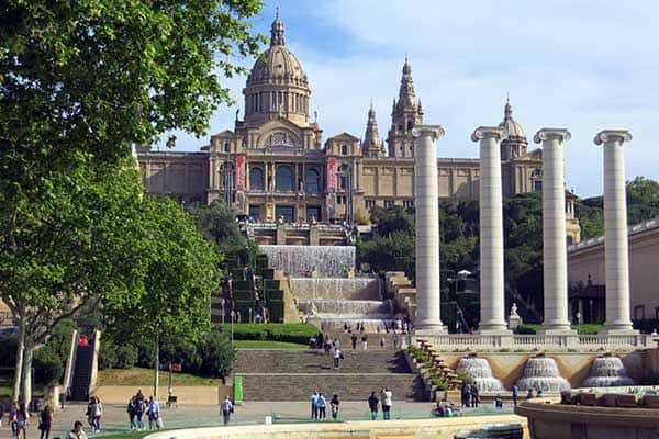 Plaza de las Cuatro Columnas con el Palau Nacional al fondo y visitantes caminando