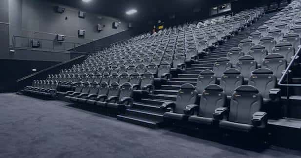 Vista general de sala de cine con butacas grises y diseño en pendiente