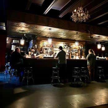 Vista del bar principal con clientes y lámparas colgantes