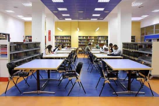 Sala de lectura con mesas y estanterías de libros