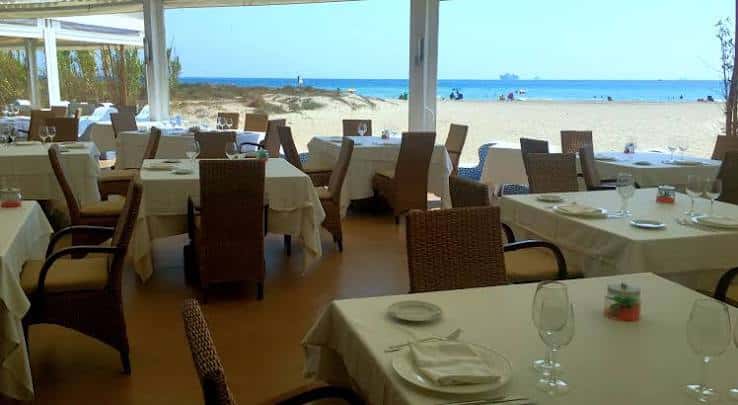 Sala principal del restaurante con mesas y vistas a la playa
